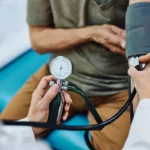 پزشک در حال اندازه گیری فشار خون یک مرد