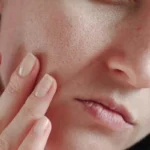 یک زن در حال بررسی پوست صورت خود