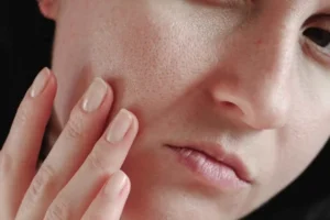 یک زن در حال بررسی پوست صورت خود