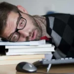 مرد خسته سرش را روی کتاب گذاشته