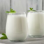 دو لیوان شیشه ای پر از دوغ با برگ نعناع روی آن ها