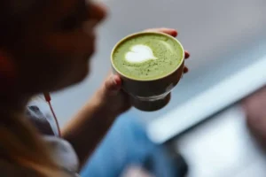 زن یا یک فنجان قهوه سبز در دست