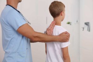 پزشک در حال معاینه قوز پشت کودک