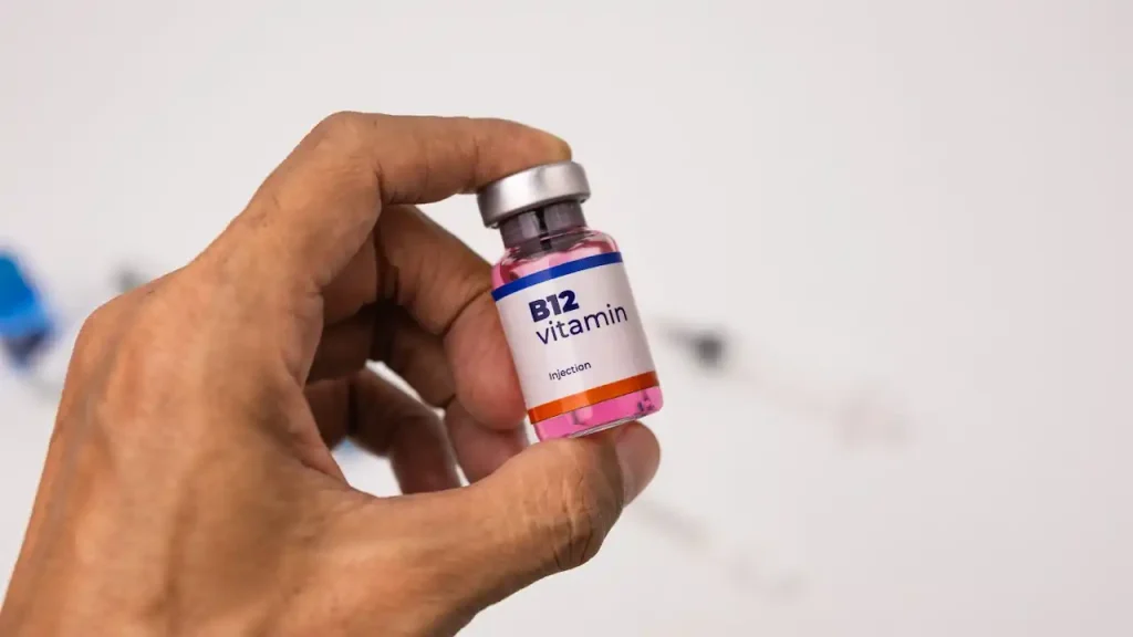 نمای نزدیک از یک ویال ویتامین B12 در دست یک مرد