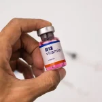 نمای نزدیک از یک ویال ویتامین B12 در دست یک مرد