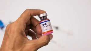 نمای نزدیک از یک ویال ویتامین B12 در دست یک مرد