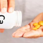 دست‌های یک زن که در حال خالی کردن تعدادی قرص از یک قوطی در دستش است